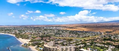 An aerial view of a coastal resort area with multiple buildings, including a large hotel with a circular central building and several smaller structures.
