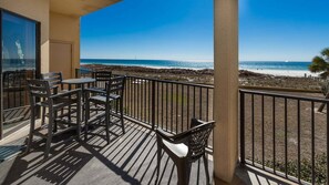 Ein Balkon mit Blick auf den Strand, ausgestattet mit einem Tisch und Stühlen.