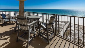A deck with a round table and four Adirondack chairs overlooking a beach. - Phoenix I 1053 2 Bedroom Condo (Orange Beach)