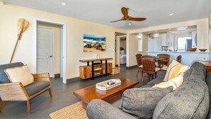 A living room with a sofa, chairs, a coffee table, a wooden TV stand, and a ceiling fan. - Royal Mauian, #314 2 Bedroom Condo (Kihei)