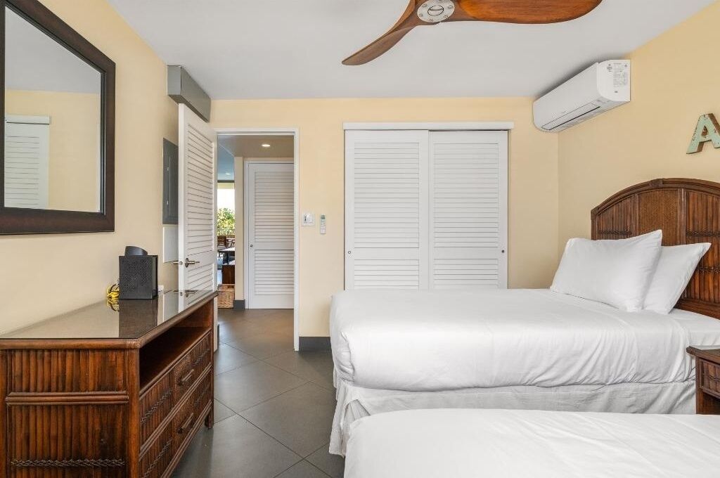A bedroom with a bed, a dresser, a mirror, and a ceiling fan.