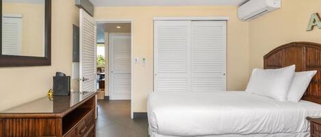 A bedroom with a bed, a dresser, a mirror, and a ceiling fan.
