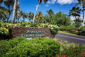 Schild für die Waikoloa Colony Villas mit Steinmauer, üppiger Vegetation und Palmen.