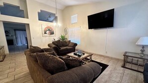 A living room with a sofa set, a coffee table, a TV mounted on the wall, and a lamp on a side table. - Wonderful 3-bedroom house with Pool and garage Las Vegas (North Las Vegas)