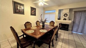 A dining room with a wooden table and chairs, a ceiling fan, and a fireplace. - Wonderful 3-bedroom house with Pool and garage Las Vegas (North Las Vegas)