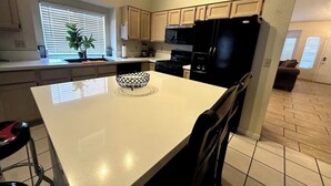 A modern kitchen with a central island, black appliances, and a dining area with chairs. - Wonderful 3-bedroom house with Pool and garage Las Vegas (North Las Vegas)
