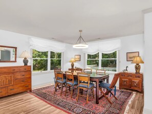 A dining room with a wooden table, chairs, and a patterned rug. - Skipjack House | an ESVR property (Mcdaniel)