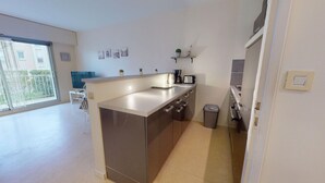 Una cuina moderna amb una illa gran, electrodomèstics integrats i vistes cap a l'exterior.