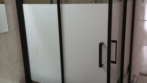 Un baño con cabina de ducha de vidrio, lavamanos blanco y retrete.