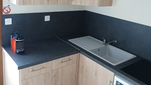 Una cocina con armarios de madera, encimera negra, pileta de acero inoxidable y lavavajillas integrado.
