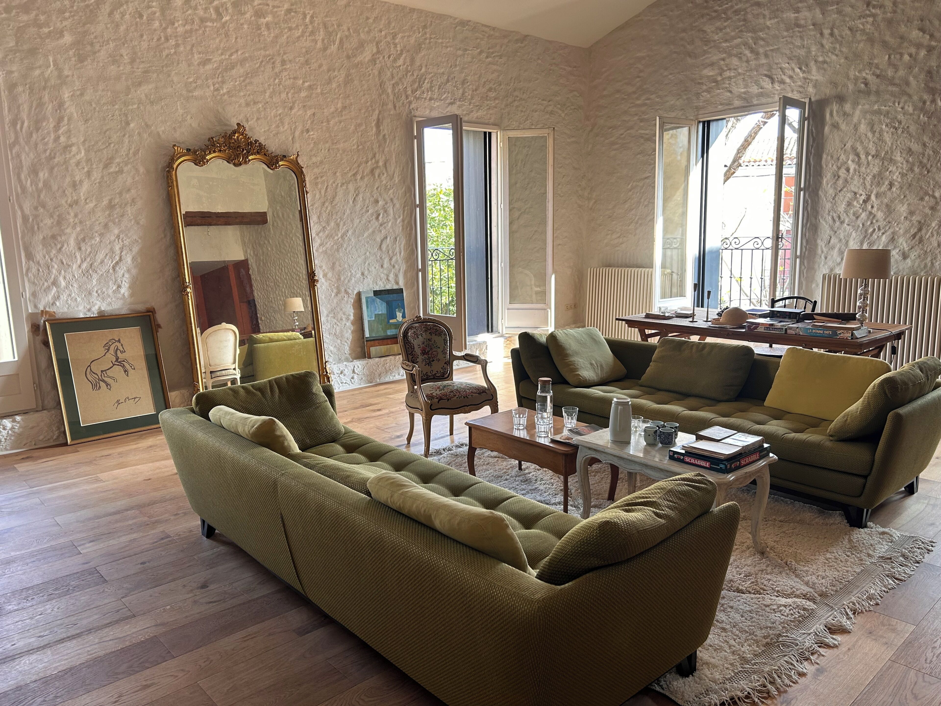 A living room with a sofa, armchair, coffee table, and a large mirror.