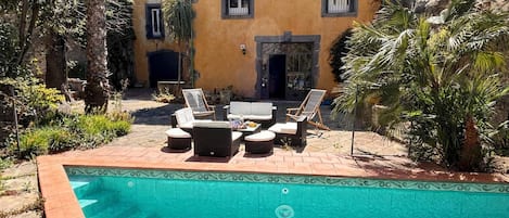 A pool area with lounge chairs and a tiled deck.