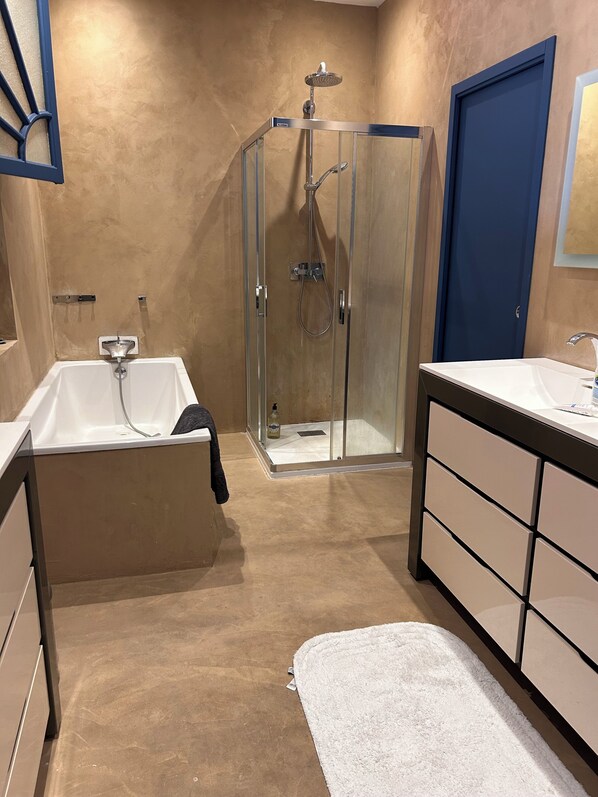 Uma casa de banho moderna com cabine de duche em vidro, banheira e toucador com lavatório.