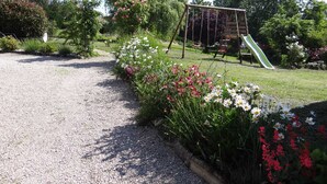 Un giardino con un vialetto ghiaioso, un’altalena e uno scivolo.