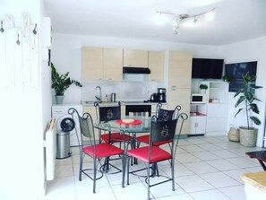 A compact kitchen with a round table and four chairs, a built-in oven, and a microwave. - Quiet 2-star gîte, less than 2km from Dole town center (Dole)