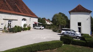 Un quartiere residenziale con un edificio in pietra, un'auto bianca parcheggiata di fronte e un cielo azzurro intenso.