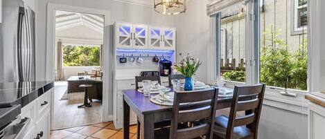 A dining area with a table set for two, a hanging light fixture, and a view of the outdoors.