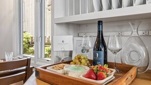 Un plateau en bois contenant des en-cas, des raisins, des fraises et une bouteille de vin, posé sur une table.