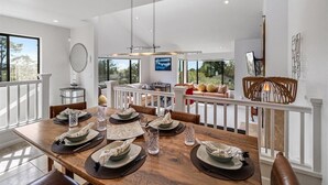 A dining area with a wooden table set for six, white railings, and a view of the outdoors. - 4062 Pretty Perfect Penthouse - Carmel-by-the-Sea (Carmel)