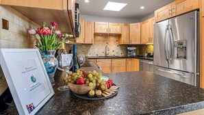 A modern kitchen with wooden cabinets, a stainless steel refrigerator, and a fruit bowl on the counter. - 4062 Pretty Perfect Penthouse - Carmel-by-the-Sea (Carmel)