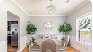 A dining room with a glass table, two chairs, a chandelier, a mirror, and potted plants. - Modern Southern Charm Near Airport & Downtown ATL (Riverdale)