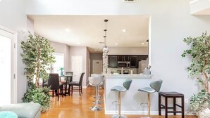 A modern kitchen with bar stools, a dining area with chairs, and a living room with a sofa. - Modern Southern Charm Near Airport & Downtown ATL (Riverdale)