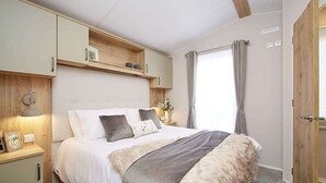 Une chambre à coucher avec un lit, des tables de chevet, une armoire et une fenêtre avec des rideaux.