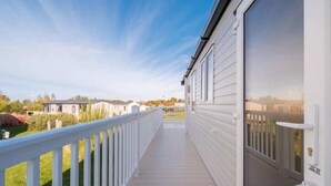 Un balcon fermé, doté d’une balustrade blanche, qui donne sur un immeuble aux grandes fenêtres.