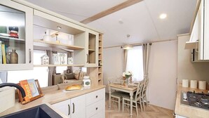 Une cuisine compacte avec un coin repas, des meubles en bois et un four encastré.