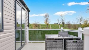 Un balcon donnant sur un champ verdoyant et des arbres, avec une balustrade blanche et deux paniers en osier.