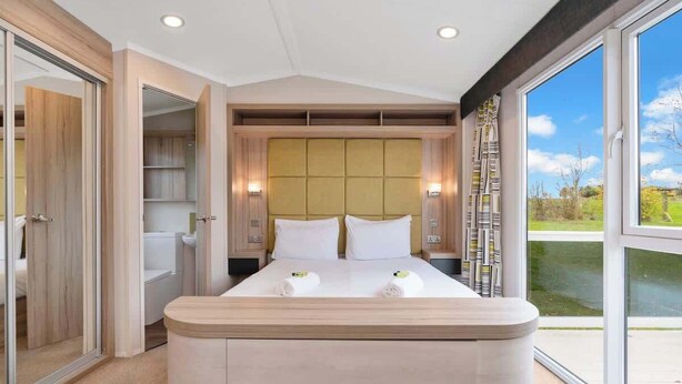 Une chambre moderne avec un grand lit, un placard intégré et une vue sur l’extérieur.