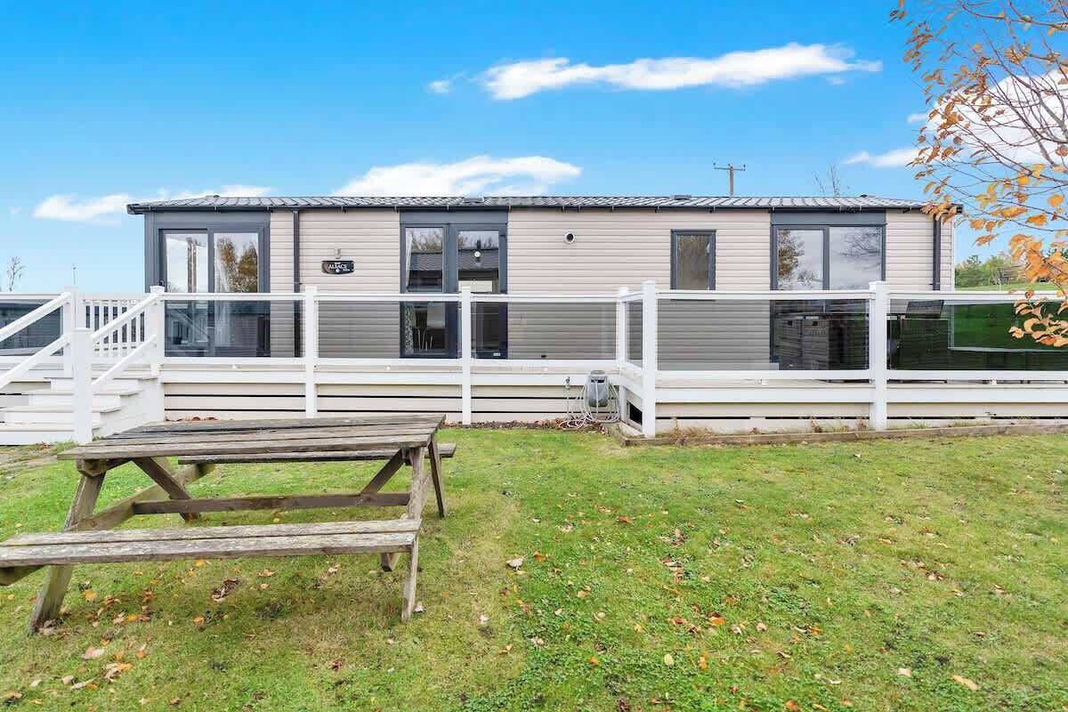 Una casa móvil de un piso con un porche cubierto y una mesa de picnic al frente.
