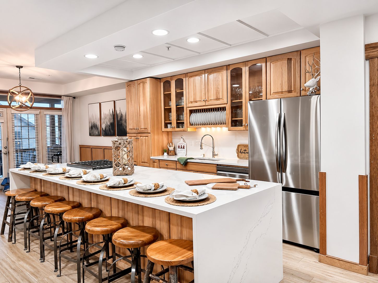 A modern kitchen with a central island, wooden cabinets, stainless steel appliances, and bar stools.