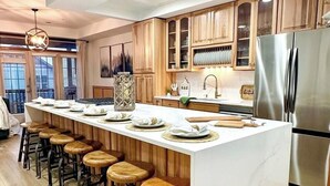 Una cocina moderna con una isla central, taburetes de madera, electrodomésticos de acero inoxidable y armarios de madera.