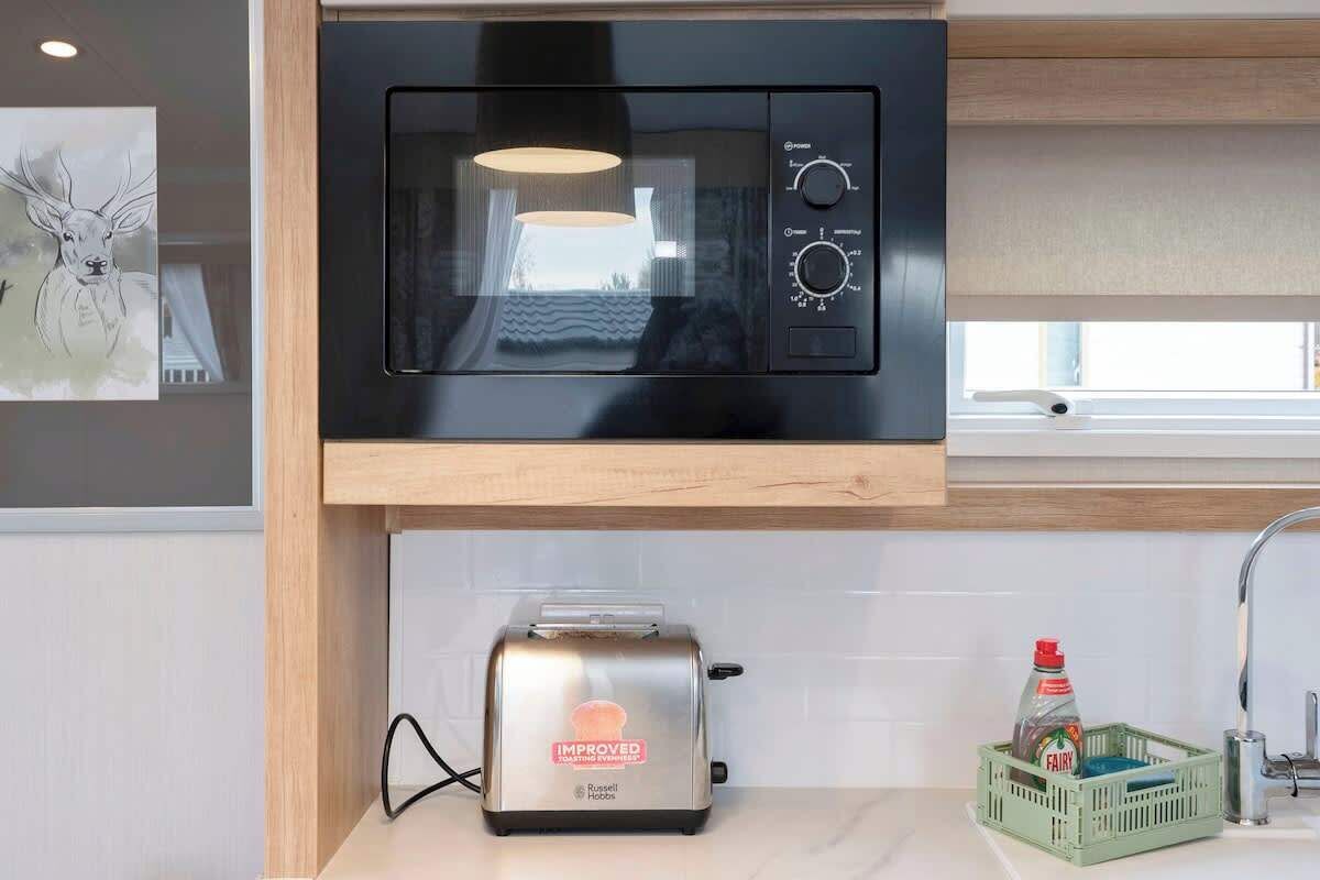 Eine Küche mit einer schwarzen Mikrowelle, einem Toaster und einer grünen Kiste mit einer Fairy-Flasche.