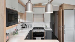 A modern kitchen with stainless steel appliances, wooden accents, and pendant lighting. - Seton Sands Gullane Luxe Lodge 3BR Sleeps 8 | WiFi (Port Seton)