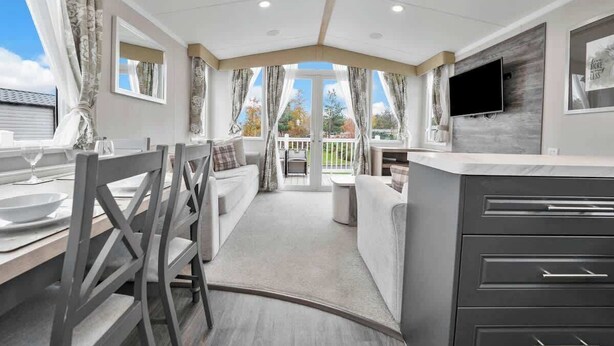 A modern kitchen with a large island, a dining area with a table and chairs, and a view of the outdoors. - Seton Sands Gullane Luxe Lodge 3BR Sleeps 8 | WiFi (Port Seton)