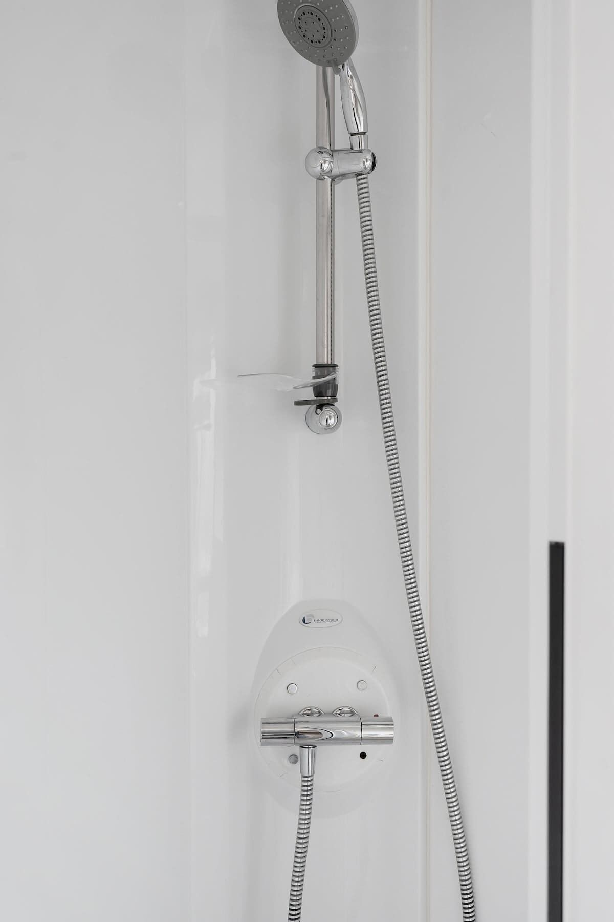 A shower with a handheld showerhead and a fixed showerhead, both with flexible hoses.