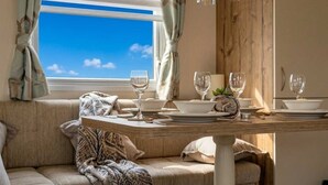 A cozy dining area with a table set for four, a window with curtains, and a view of the sky.