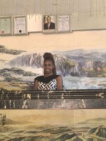 Una persona de pie frente a un mural con una cascada y montañas.