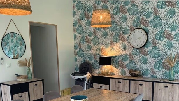 A modern kitchen with a wooden dining table, grey chairs, and a tropical leaf-patterned wallpaper. - Large family home near the canal in Agen (Agen)