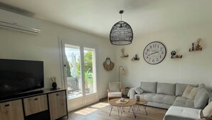 A modern living room with a flat-screen TV, a sofa, a coffee table, and a large window. - Large family home near the canal in Agen (Agen)