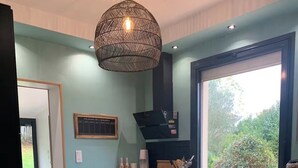 A kitchen with a large window, a hanging light fixture, and a wooden floor. - Large family home near the canal in Agen (Agen)