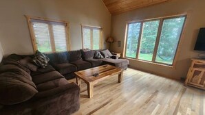 A cozy living room with a sectional sofa, a wooden coffee table, and large windows offering a view of the outdoors. - Sunsets on Beaver Dam Lake (Cumberland)
