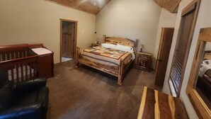 A bedroom with a wooden bed, a crib, a nightstand, and a ceiling fan. - Sunsets on Beaver Dam Lake (Cumberland)