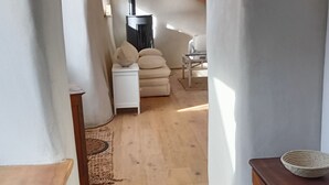 A narrow hallway with wooden flooring, a white sofa, and a small table with a basket.