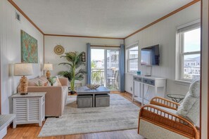 A living room with a sofa, coffee table, TV, and a large window with a view. - Channel Front 2 Bedroom Condo with a Pool! Across from the Ocean (Garden City Beach)