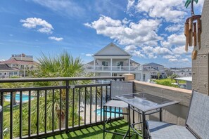 A balcony with a pool, a chair, and a table. - Channel Front 2 Bedroom Condo with a Pool! Across from the Ocean (Garden City Beach)