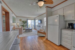 A compact kitchen with a refrigerator, coffee maker, and a dining area with a table and chairs. - Channel Front 2 Bedroom Condo with a Pool! Across from the Ocean (Garden City Beach)