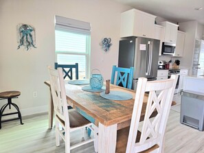 A dining area with a wooden table, blue chairs, and a blue lantern. - 🐠Easy Beach Access | Game Room | Pet Friendly | Fish-n-Ships⚓ (Windmark Beach)